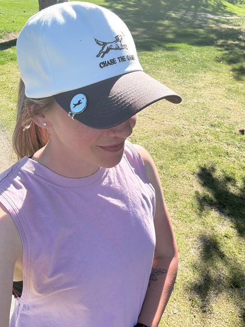 Person wearing a white and gray cap with a logo on a grassy background